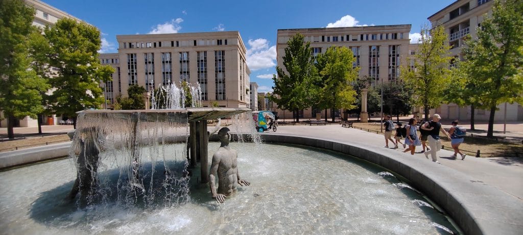 Usagers se déplaçant à pied et en vélotaxi autour de la fontaine de la place de Thessalie, quartier Antigone à Montpellier