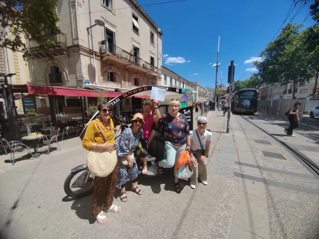 Vélotaxi, tramway et dernier kilomètre à Montpellier Groupe de personnes avec un vélotaxi près du tramway dans le centre-ville de Montpellier.